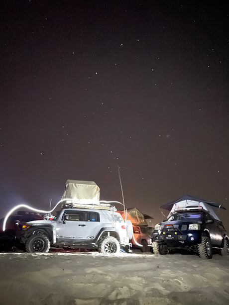 Two customized SUVs with rooftop tents under a starry night sky, ideal for an RV rental inspired adventure.
