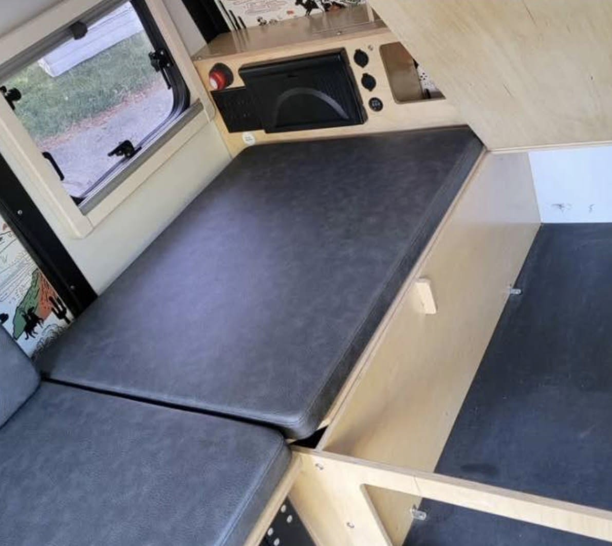  is ready for outdoor adventures at sunset.|This rv rental offers stunning views! Looking out at a peaceful forest campsite through an open top window — photo 4