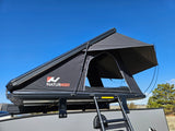 Black NaturNest rooftop tent deployed on an RV rental, with a ladder for easy access. Ready for outdoor camping.