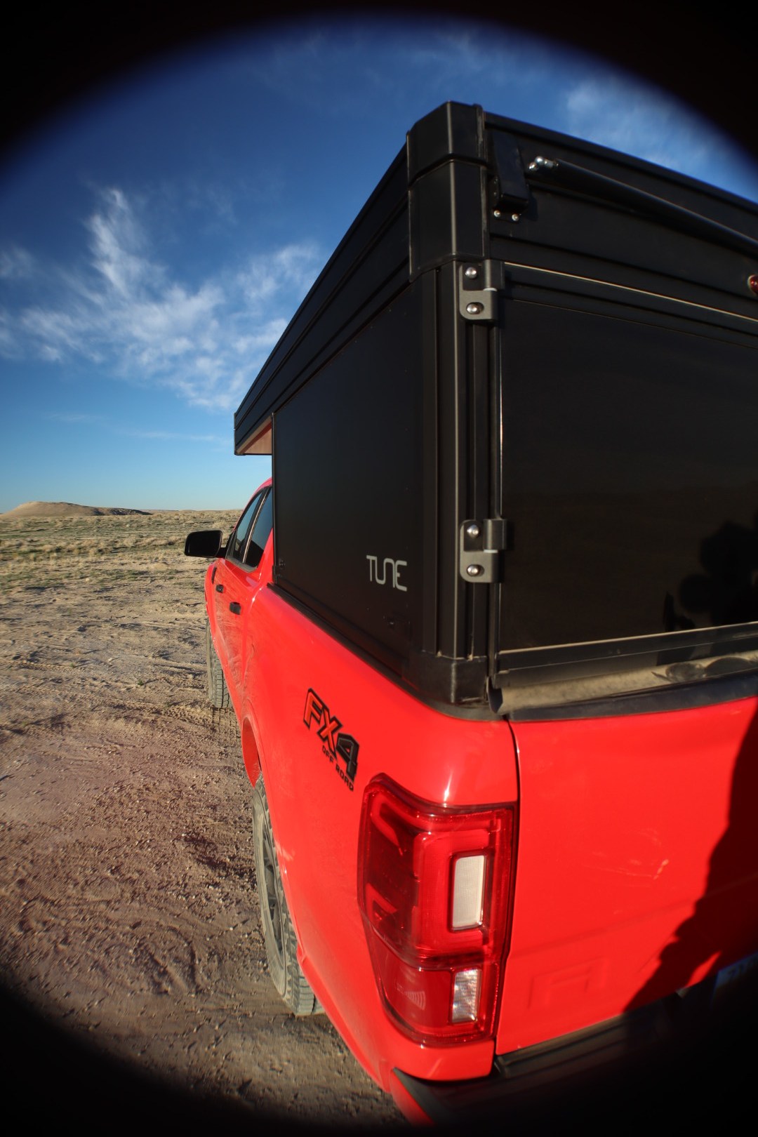  parked in a desert landscape. Perfect overland rv rental for off-road adventures.|RV rental: Red pickup truck with a black pop-top truck camper. Perfect for off-road adventures and outdoor camping. — photo 4