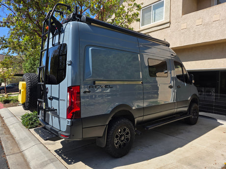 Gray Mercedes Sprinter Revel 4x4 camper van for rv rental. Equipped for adventure with roof rack, ladder, off-road tires.