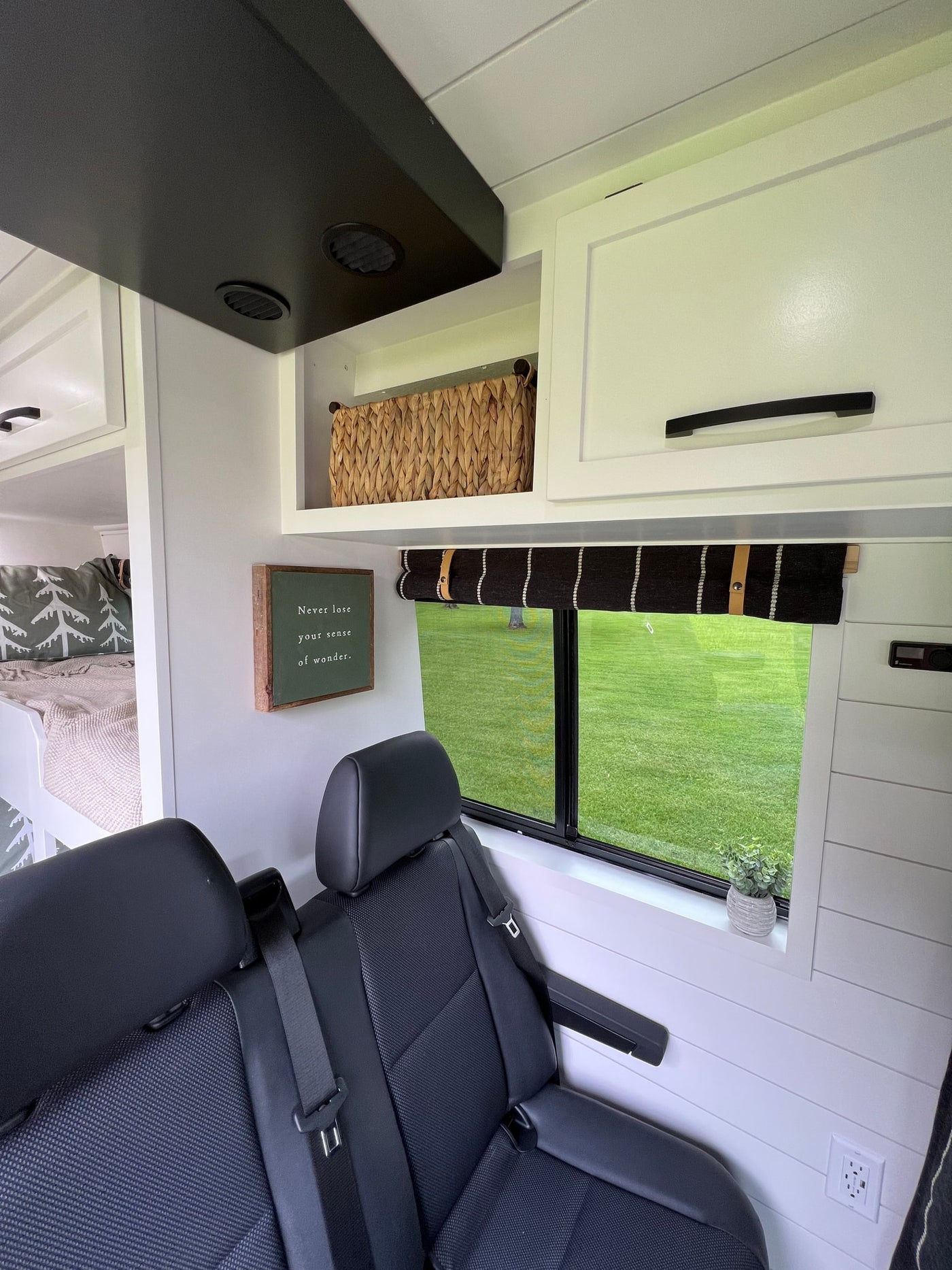 Modern RV rental interior: bunk beds, comfy passenger seats, overhead storage, and window view of green landscape. — photo 6