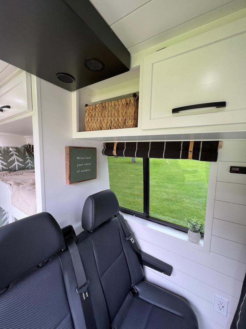 Modern RV rental interior: bunk beds, comfy passenger seats, overhead storage, and window view of green landscape. — photo 6
