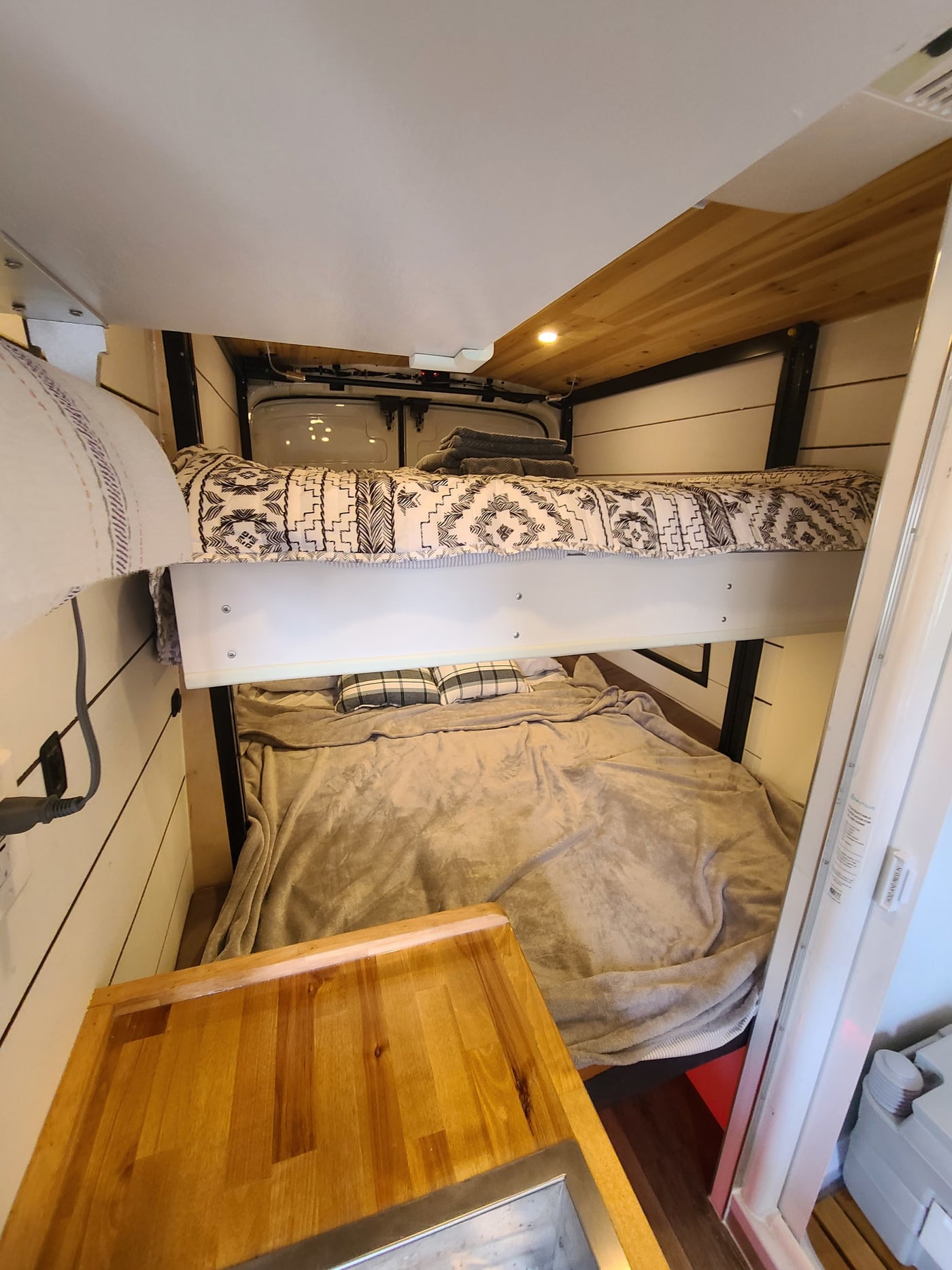 Compact RV rental campervan interior featuring comfortable bunk beds, a wooden counter, and efficient use of space. — photo 9