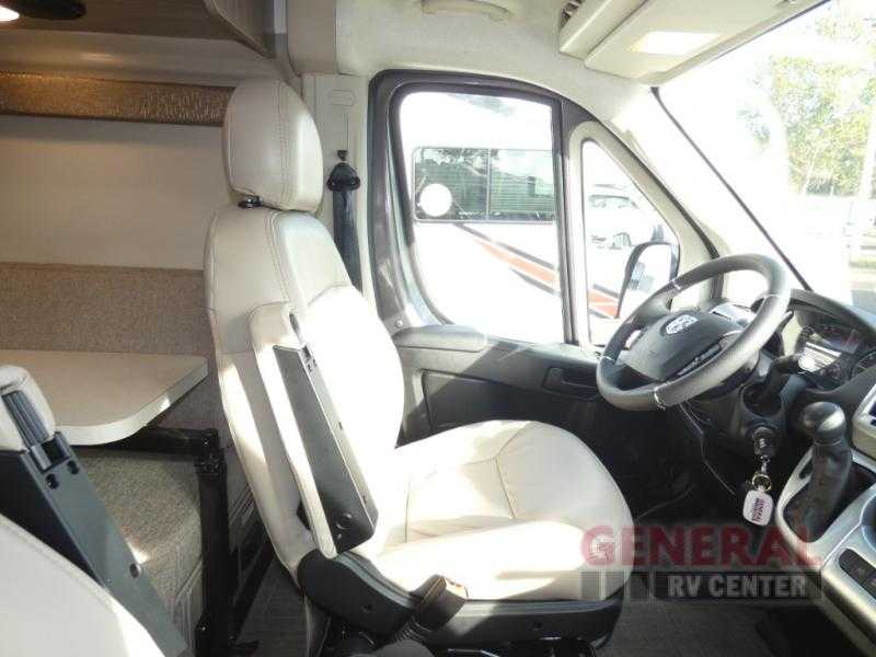 RV rental interior: Spacious cockpit with light-colored driver's seat, steering wheel, and living area access. — photo 11
