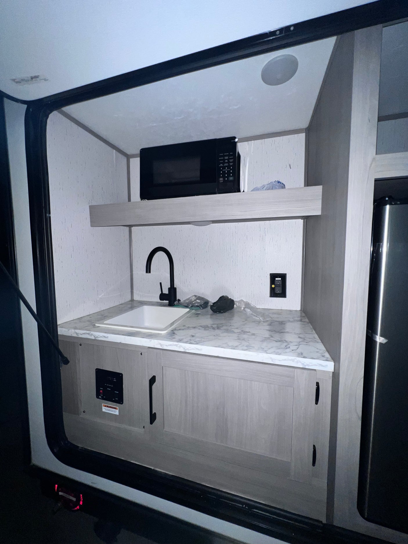 Inside an RV rental: a compact kitchen with sink, microwave, and refrigerator for convenience.