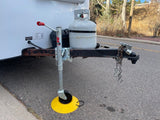 RV rental trailer hitch setup with jack on yellow footpad, propane tank, and safety chains, ready for a trip.