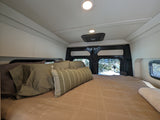 Cozy RV rental bed with a snowy view out the back doors. Ideal for winter getaways.