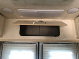 View inside an RV rental showing an open overhead cabinet, two ceiling lights, and pleated window blinds.