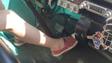 Leg in red shoe pressing gas pedal in a vintage RV rental. Dashboard features an old radio and Smokey Bear sticker.