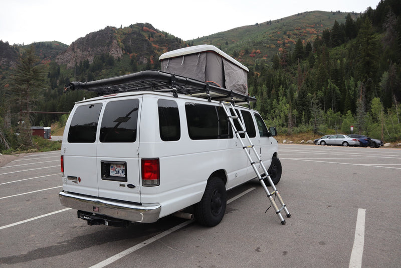Explore nature with this white rv rental camper van, featuring a rooftop tent & ladder, parked by autumn mountains. — photo 5