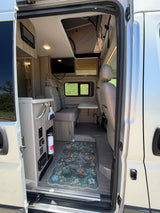 Inviting rv rental interior with a floral rug, comfortable seating, dining table, kitchenette, and pop-top roof.