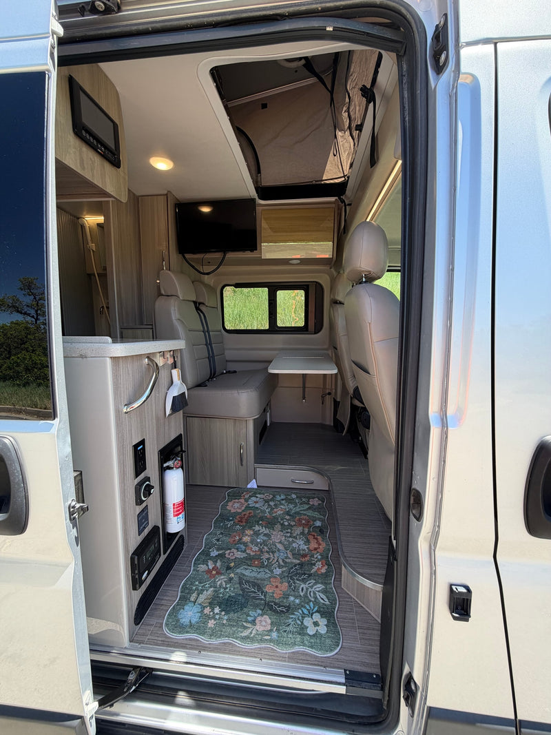 Inviting rv rental interior with a floral rug, comfortable seating, dining table, kitchenette, and pop-top roof. — photo 15