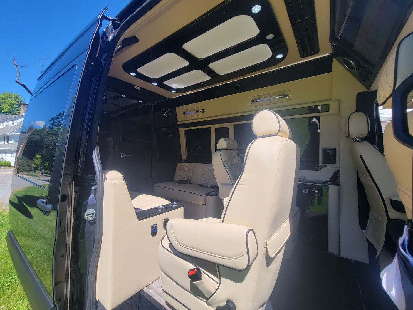 Spacious RV rental interior featuring plush cream leather seats, elegant black accents, and modern lighting for ultimate comfort.
