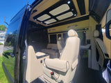 Spacious RV rental interior featuring plush cream leather seats, elegant black accents, and modern lighting for ultimate comfort.