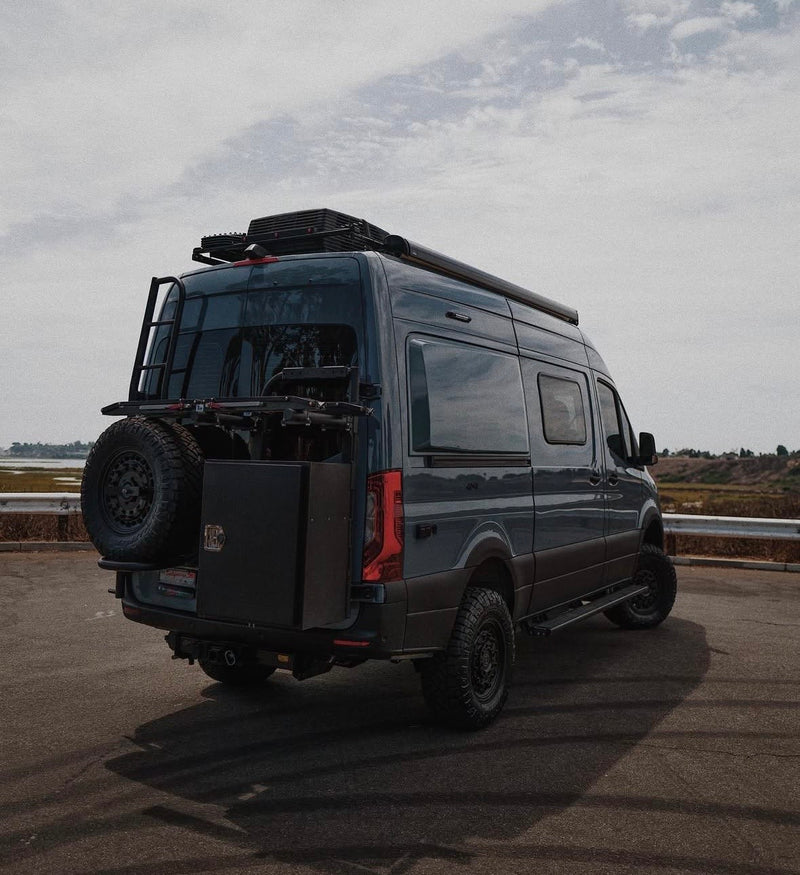 Dark gray Mercedes Sprinter van, an ideal rv rental. Features off-road tires, a ladder, storage box, and roof rack. — photo 3