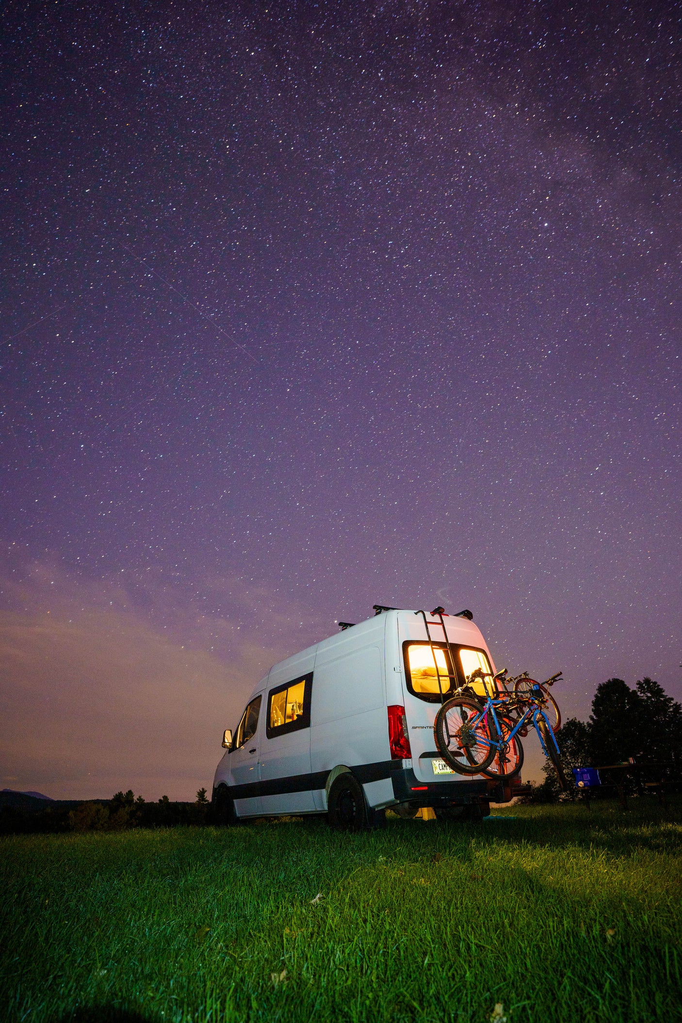 Night sky adventure! This illuminated RV rental with bikes offers cozy camping under a brilliant starry night.