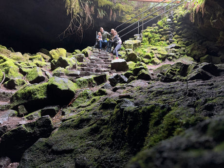 Family enjoying a mossy cave entrance, a perfect stop for your next RV rental adventure.