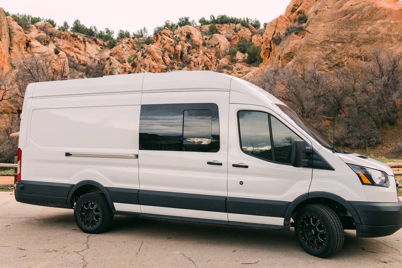 White RV rental campervan parked amidst stunning red rock formations, ready for adventure.