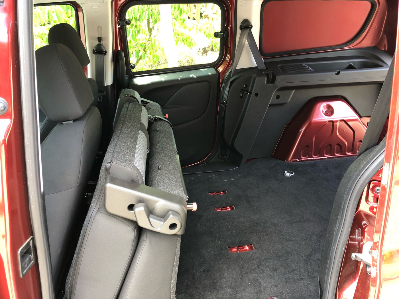 RV rental interior: Rear seats folded forward, creating a vast, dark carpeted cargo area with floor tie-downs for storage. — photo 9