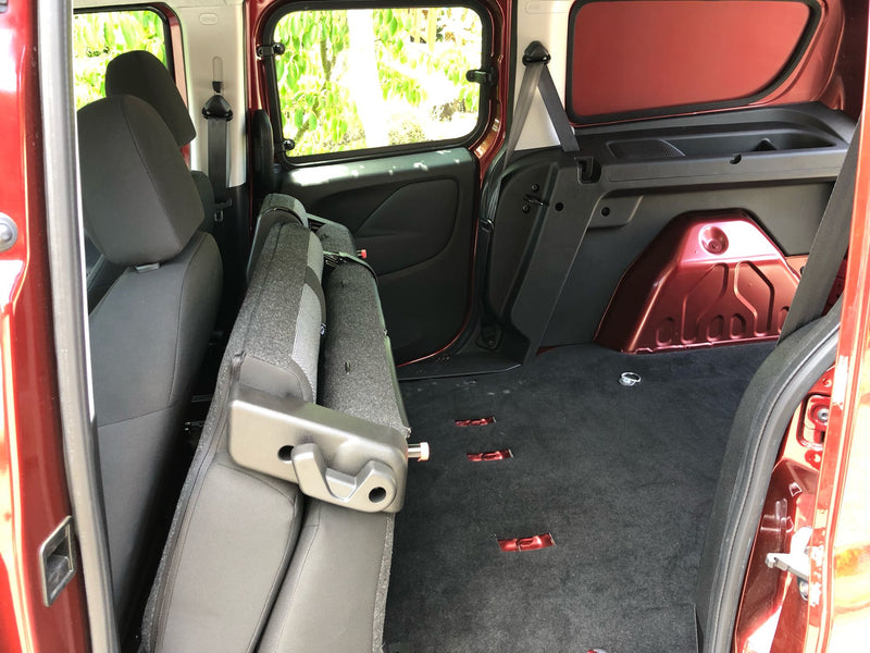 RV rental interior: Rear seats folded forward, creating a vast, dark carpeted cargo area with floor tie-downs for storage. — photo 9