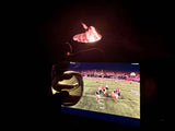 Cozy RV rental night: football game on screen, drink in hand, and a warming fire pit. Perfect relaxation.