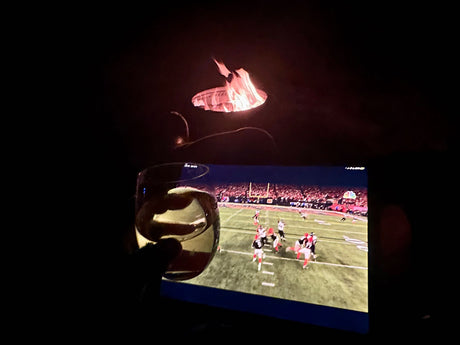 Cozy RV rental night: football game on screen, drink in hand, and a warming fire pit. Perfect relaxation.
