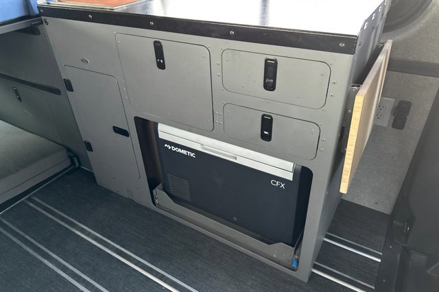 RV rental interior: Dometic CFX fridge on slide-out, modular cabinets, and fold-down table for adventure.