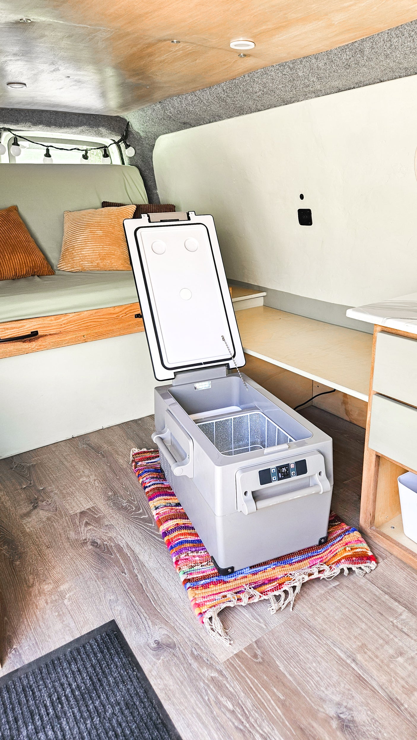 Cozy RV rental interior with a portable cooler, comfy bench, and wood flooring. Perfect for your next adventure!