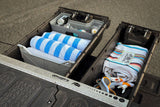 Organized truck bed storage with rolled towels, drinks on ice, a blanket, and flippers, ideal for an RV rental adventure.