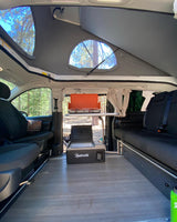 Pop-top RV rental interior: A compact kitchen setup with stove and fridge, plus convertible seating, ideal for nature trips.