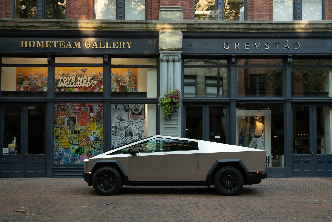 A striking Tesla Cybertruck, resembling a unique RV rental, sits on a brick street outside an art gallery. Electric adventure awaits. — photo 6
