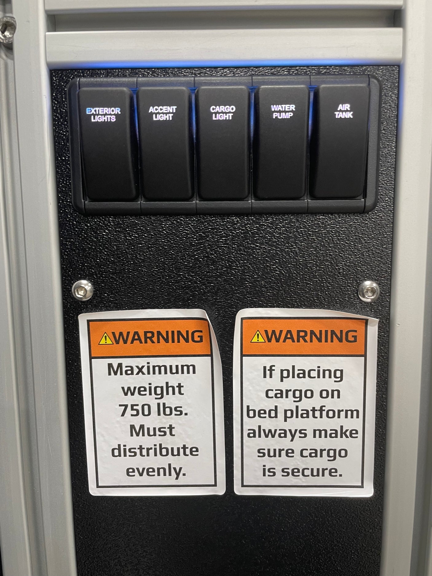 RV rental control panel showing light/pump/air switches & cargo weight/secure warnings for safe operation.