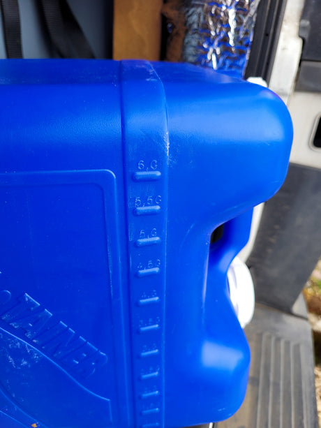 Close-up of a blue portable water tank, showing gallon measurements for an RV rental.