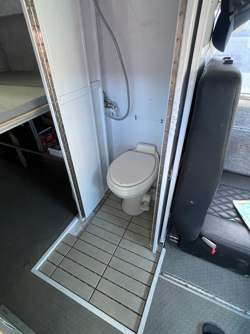  parked on concrete under a cloudy sky.|RV rental interior featuring practical overhead storage — photo 6