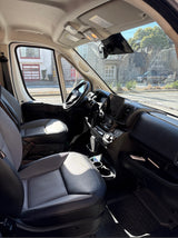 Inviting front interior of an RV rental: driver's area with dashboard, seats, and a clear view to the road.