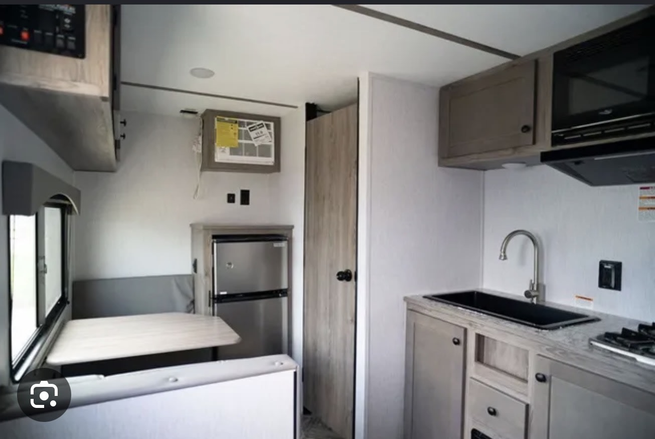  next to a functional kitchenette with a black sink.|This RV rental features a bright interior with a modern kitchen area including a sink