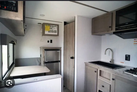  next to a functional kitchenette with a black sink.|This RV rental features a bright interior with a modern kitchen area including a sink