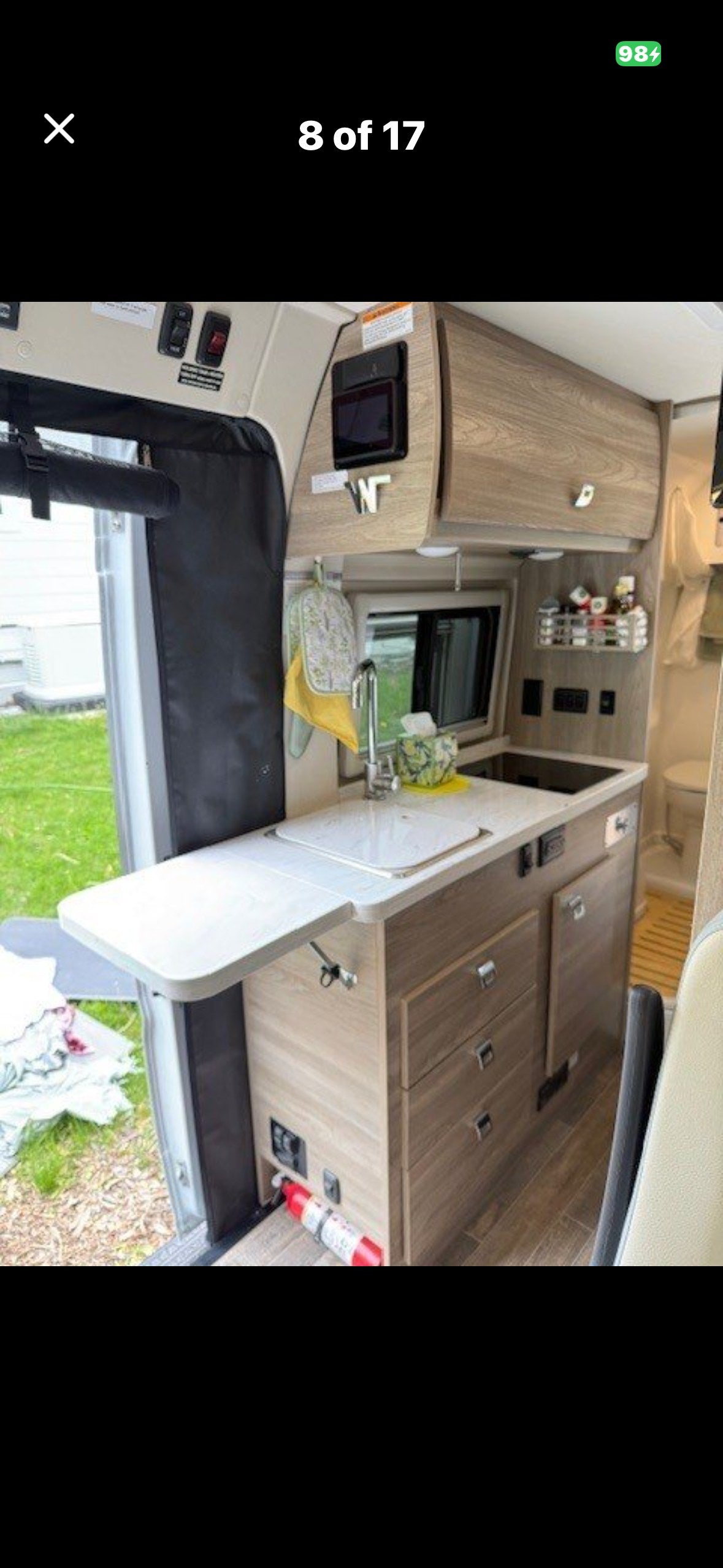 Functional kitchen in this RV rental, with sink, microwave, cabinets, and pull-out counter. Fire extinguisher visible for safety.