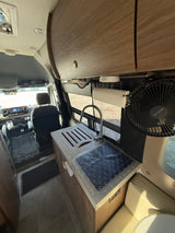 View inside an RV rental showing the kitchen area with a sink, faucet, and a spacious counter, leading to the driver's cabin.