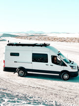 White camper van (rv rental) in white sand dunes. A dog peeks from the window. Perfect for adventurous travel!