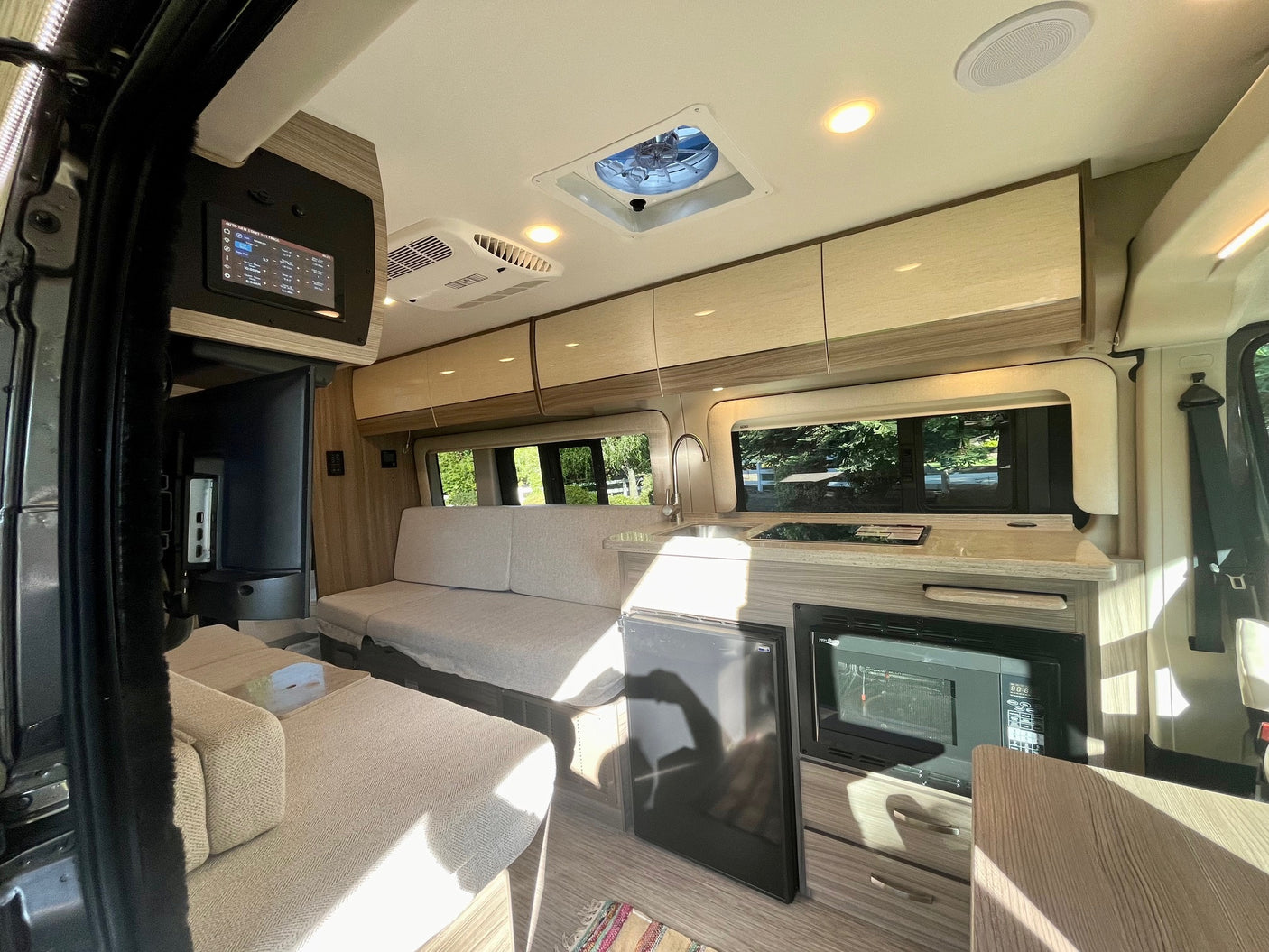 This rv rental interior features a cozy living area, a compact kitchenette with appliances, and a central control panel.