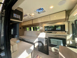 This rv rental interior features a cozy living area, a compact kitchenette with appliances, and a central control panel.