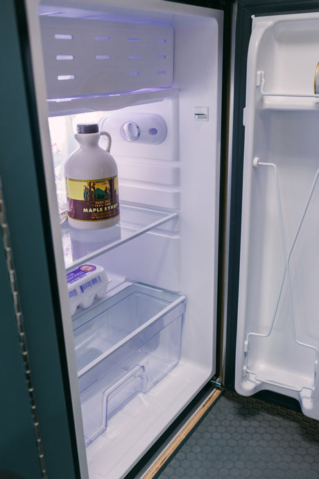 A clean RV rental fridge holds Trader Joe's maple syrup & Egg-Land's Best eggs, perfect for your next camping adventure.