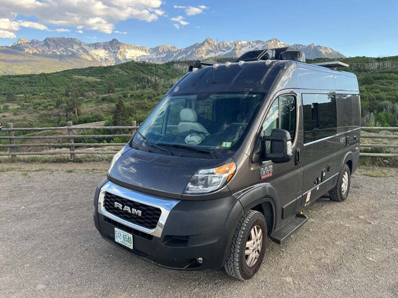 Dark grey RAM ProMaster camper van, perfect rv rental, parked on gravel with stunning snow-capped mountains and lush forests. — photo 1
