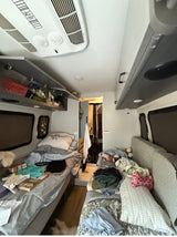 rv rental interior: two sleeping areas with personal items, overhead AC unit, and storage cabinets.