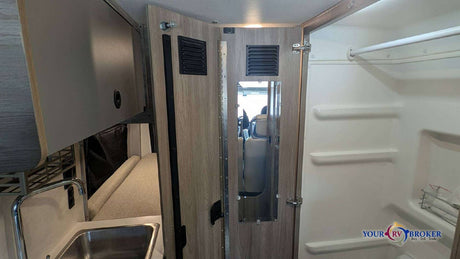 Experience a compact RV rental interior with a kitchen sink, mirrored partition, and an integrated shower for convenient travel.