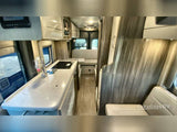Interior of an **rv rental**: compact kitchen with sink/stovetop on left, living/dining space rear. Modern, functional design.