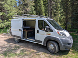 White Ram ProMaster camper van, possibly an rv rental, parked in a sunny forest with open side door.