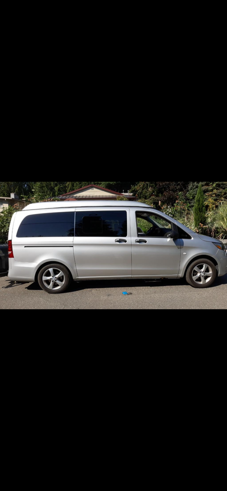 Silver Mercedes-Benz camper van for RV rental. Side profile shows tinted windows & raised roof, parked on asphalt.